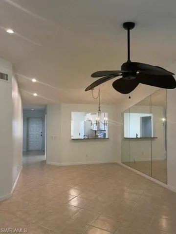 Empty room featuring ceiling fan with notable chandelier and light tile patterned floors