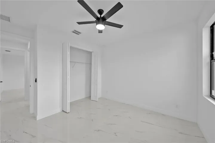 Unfurnished bedroom with ceiling fan and a closet