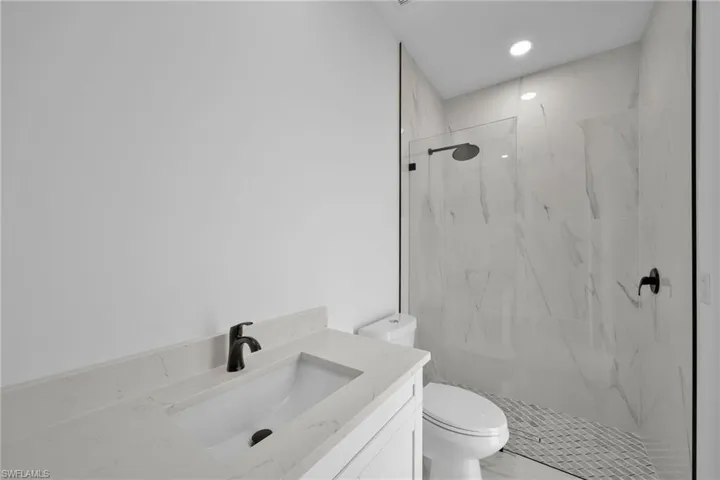Bathroom with tiled shower, vanity, and toilet