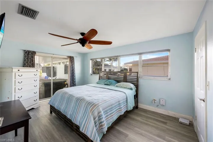 Bedroom with visible vents, access to exterior, wood finished floors, baseboards, and ceiling fan
