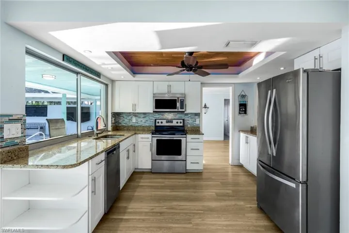 Kitchen with light stone countertops, stainless steel appliances, a raised ceiling, and a sink