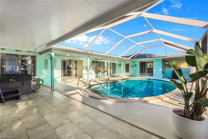 Pool with glass enclosure, a patio, and a hot tub
