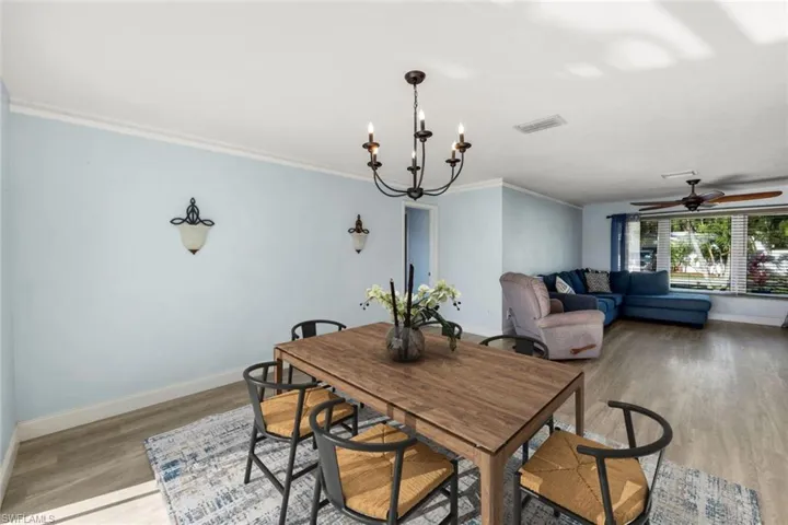 Dining area featuring visible vents, crown molding, baseboards, ceiling fan with notable chandelier, and light wood-style flooring