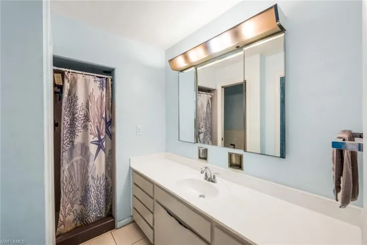 Full bathroom featuring tile patterned floors, curtained shower, and vanity