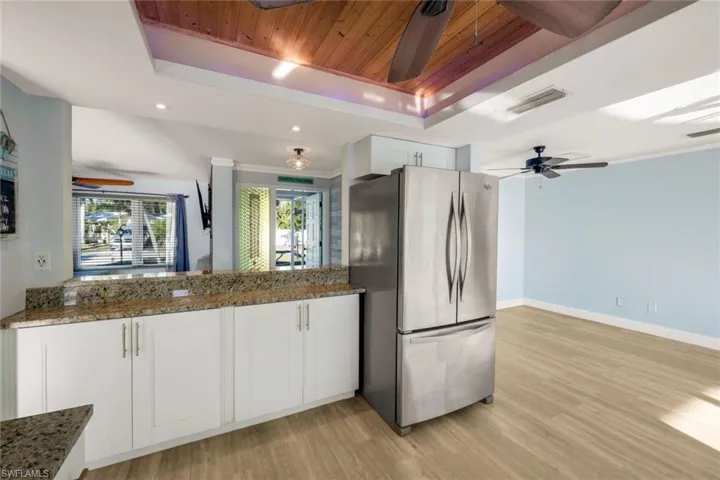 Kitchen featuring visible vents, freestanding refrigerator, a raised ceiling, wood ceiling, and ceiling fan