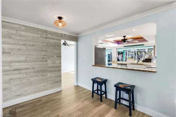 Kitchen with wood finished floors, a sink, ornamental molding, ceiling fan, and appliances with stainless steel finishes