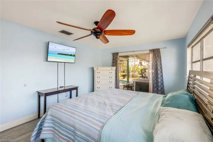 Bedroom featuring visible vents, ceiling fan, baseboards, wood finished floors, and access to outside