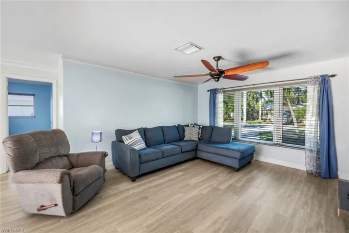 Living area with visible vents, light wood-style flooring, baseboards, and ceiling fan
