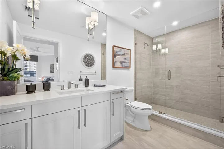 Contemporary bathroom featuring a spacious glass-enclosed shower with tiled walls and a large vanity with a white countertop and double-door cabinetry