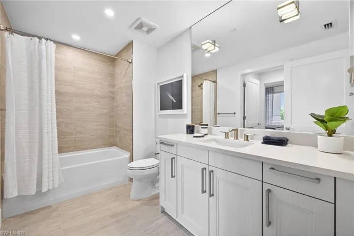Bathroom featuring a white vanity with dual sinks, a large wall-mounted mirror, and contemporary fixtures