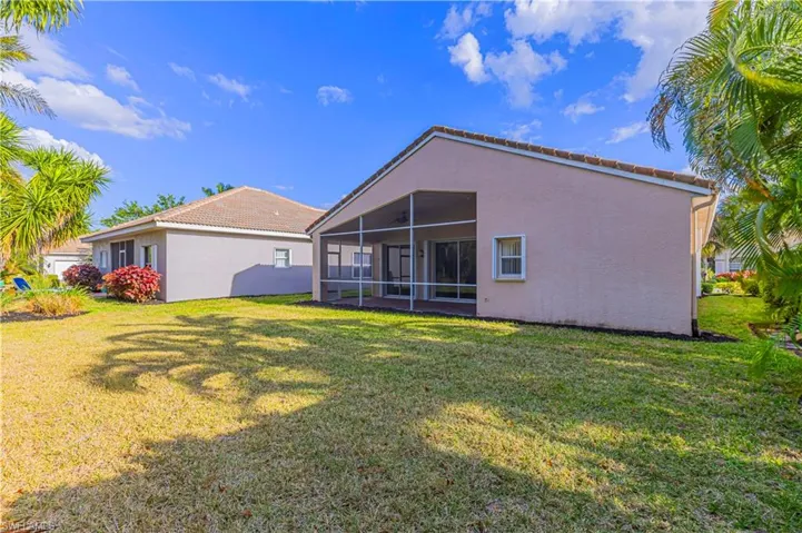Rear view of house with stucco siding, a sunroom, and a lawn