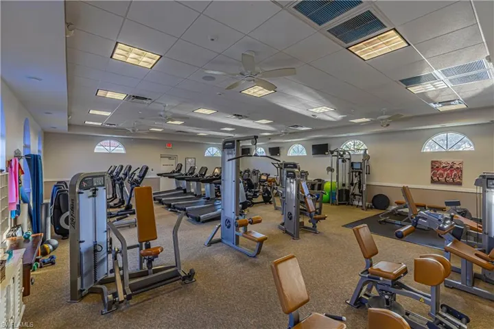Workout area with plenty of natural light, visible vents, a paneled ceiling, and a ceiling fan