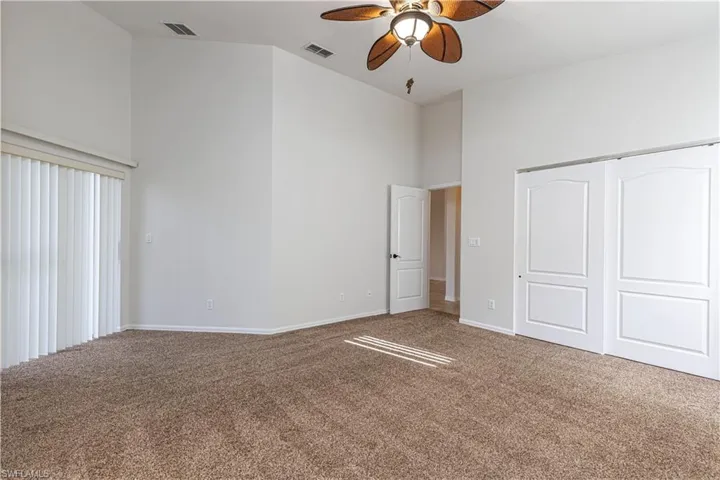 Unfurnished bedroom featuring a closet, carpet floors, a towering ceiling, and visible vents