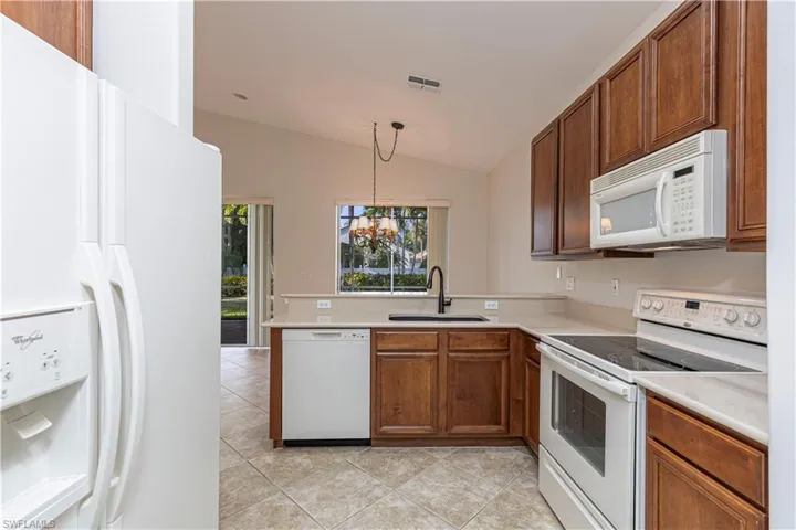 Kitchen with white appliances, light countertops, a sink, and a peninsula