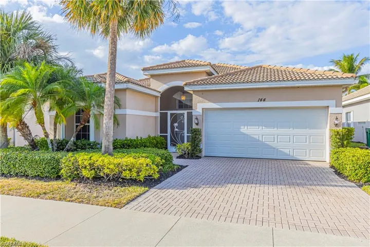 View of front facade featuring stucco siding, a tile roof, a garage, and decorative driveway