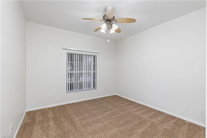 Carpeted spare room with baseboards and a ceiling fan