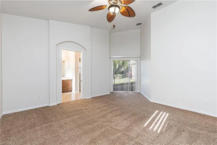 Spare room featuring baseboards, carpet floors, visible vents, and a ceiling fan