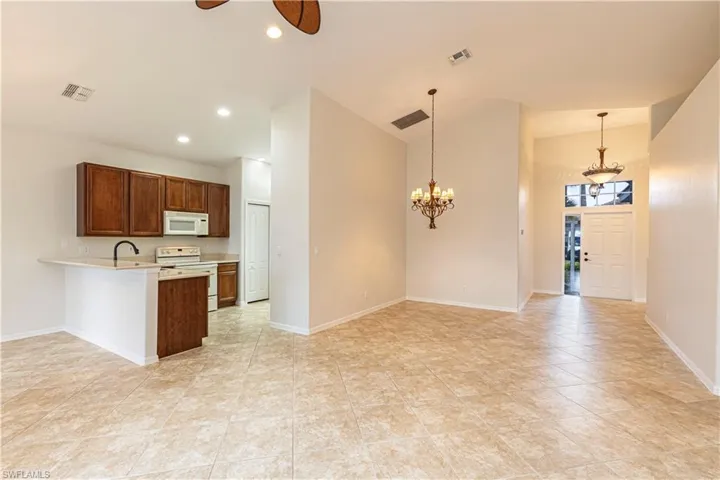 Kitchen with light countertops, visible vents, a peninsula, and white appliances