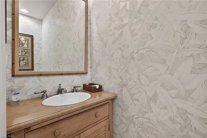 Half bath featuring wallpapered walls and vanity