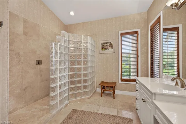 Primary Bathroom with vanity, a walk in shower, wallpapered walls, and recessed lighting