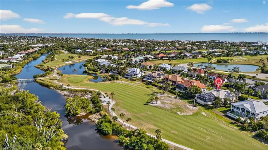 Aerial view of residential area featuring a nearby body of water and a local golf course