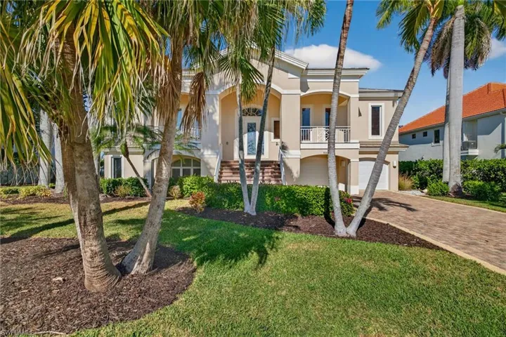 View of property with a garage, decorative driveway, and stairway