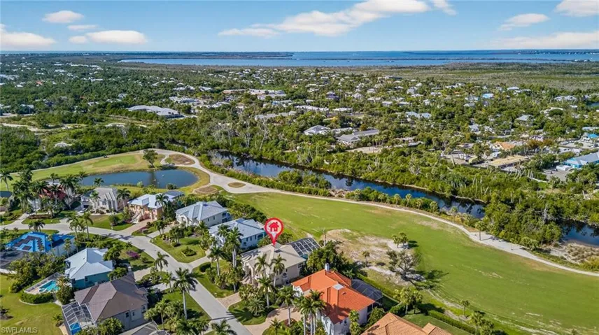 Aerial overview of property's location featuring a nearby body of water, a golf course, and nearby suburban area