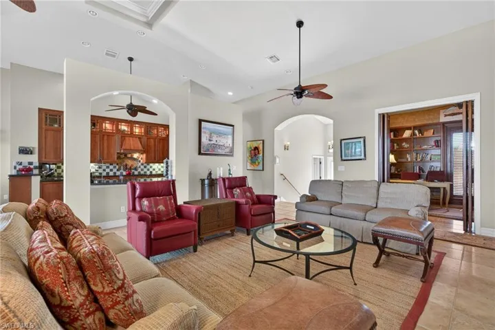Living room featuring a ceiling fan, recessed lighting, arched walkways, lofted ceiling, and light tile patterned floors