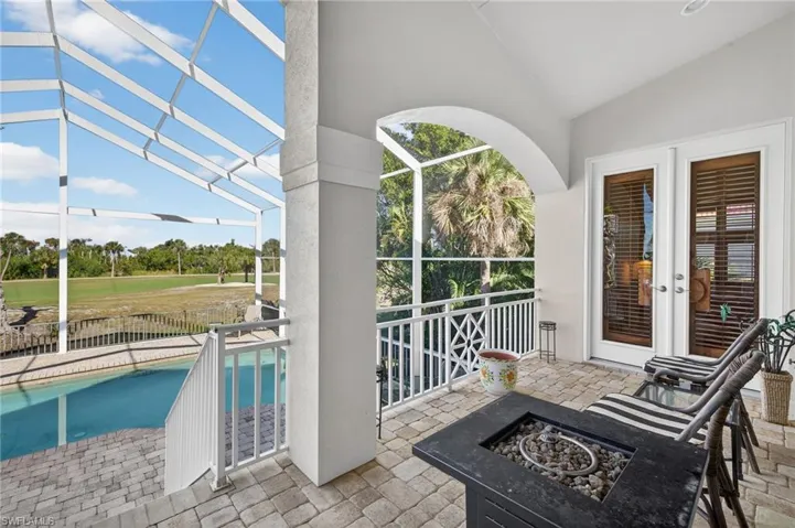 Patio with a sunroom, an outdoor fire pit, view of pool, and view of scattered trees