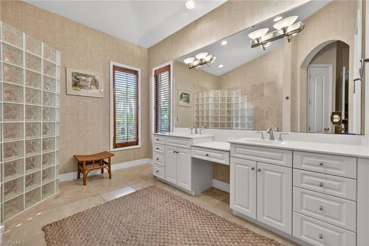 Primary Bathroom featuring wallpapered walls, double vanity, and a chandelier