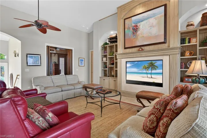 Living room with built in features, a ceiling fan, arched walkways, and recessed lighting