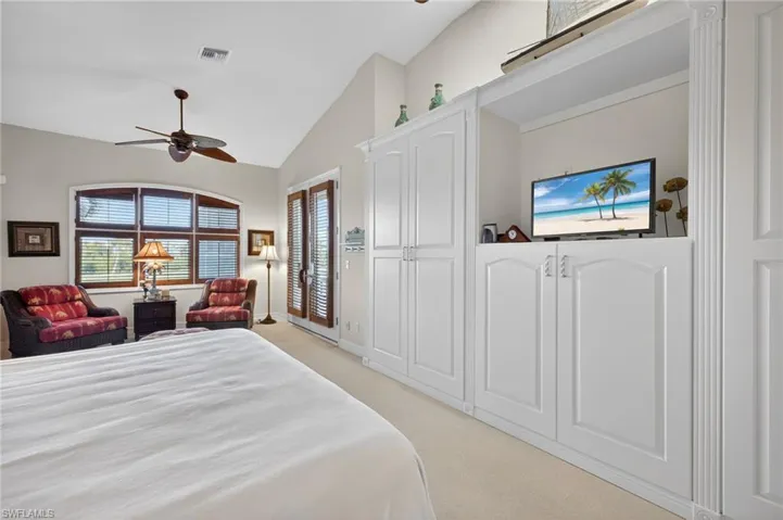 Primary Bedroom with a ceiling fan, vaulted ceiling, light colored carpet, and access to exterior