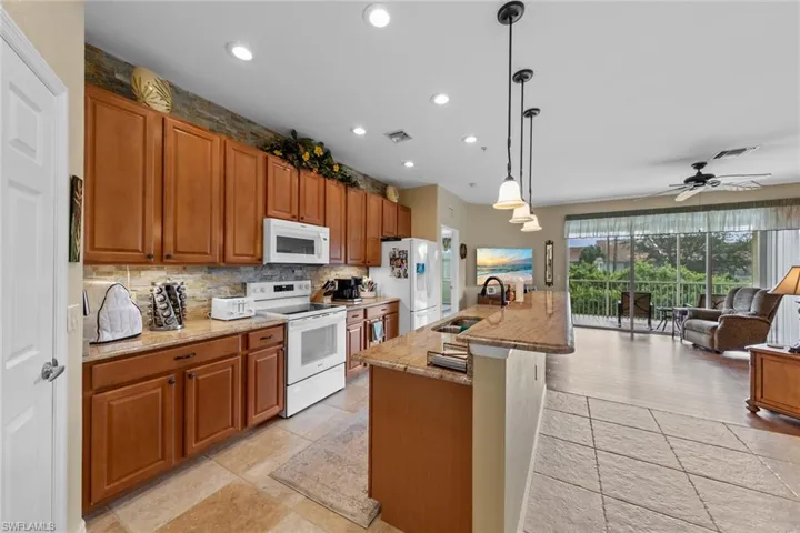 Kitchen with pendant lighting, white appliances, sink, ceiling fan, and light hardwood / wood-style floors