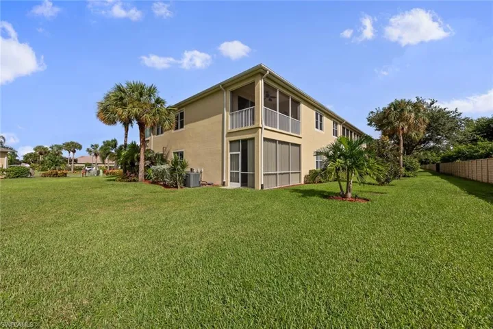 Back of property with a balcony, a yard, and central AC unit