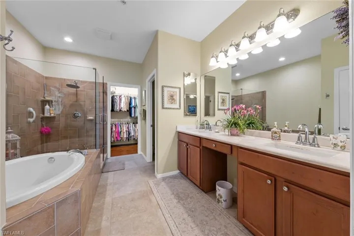 Bathroom featuring tile patterned flooring, shower with separate bathtub, and vanity