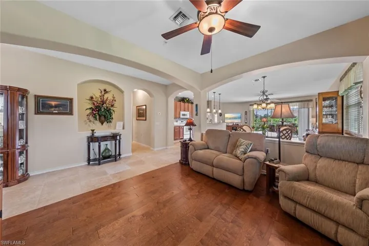 Living room with ceiling fan with notable chandelier and light hardwood / wood-style floors