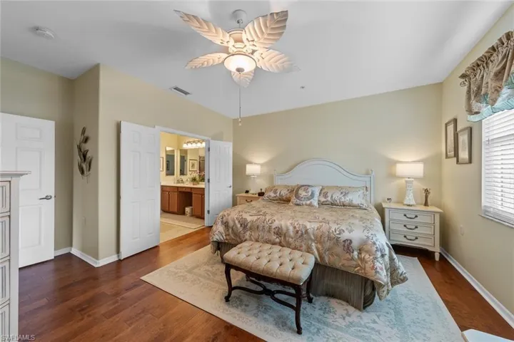 Bedroom with dark wood-type flooring, ceiling fan, and ensuite bathroom