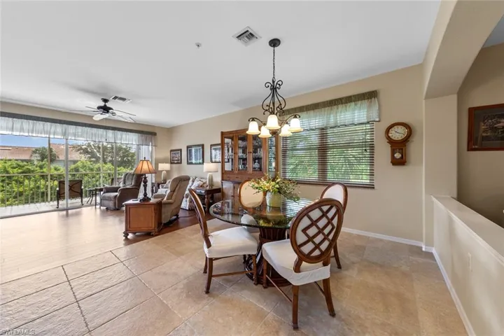 Dining room featuring ceiling fan with notable chandelier and light tile patterned flooring