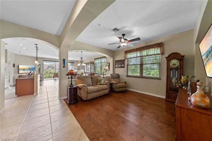 Living room with ceiling fan with notable chandelier and light hardwood / wood-style floors