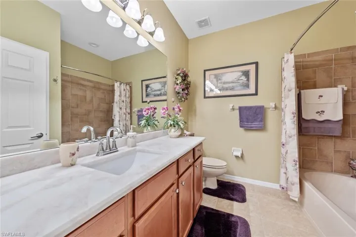 Full bathroom featuring vanity, toilet, shower / bath combo with shower curtain, and tile patterned flooring