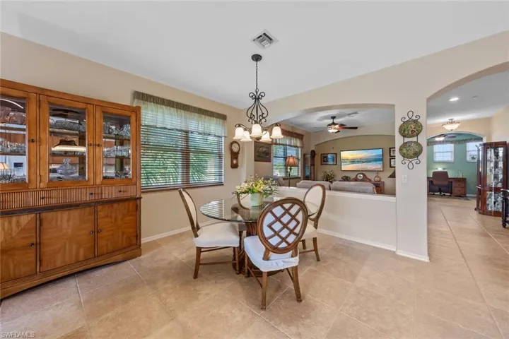 Tiled dining space featuring ceiling fan with notable chandelier