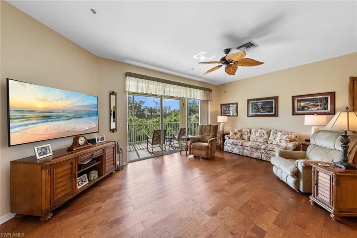 Living room with ceiling fan and dark hardwood / wood-style floors