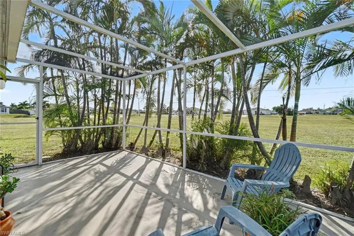 Screen-enclosed patio featuring concrete flooring and surrounding mature palm trees