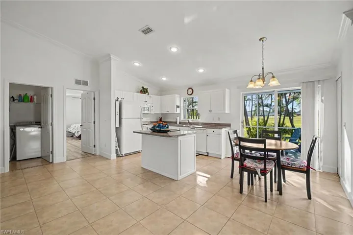 Kitchen featuring a center island, white cabinetry, neutral stone-finish countertops, ceramic tile flooring, and recessed lighting