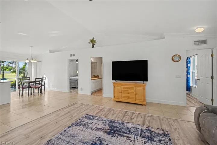 Open-concept living space featuring vaulted ceilings, light-tone tile flooring, and wood-finish flooring