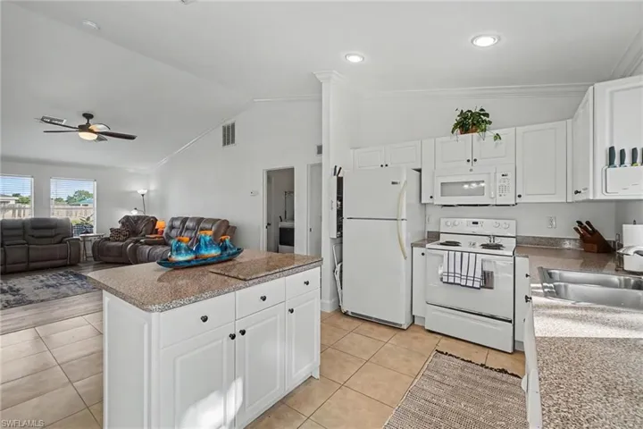 Kitchen featuring white cabinetry, an island with stone-finish countertops, recessed lighting, and tile flooring