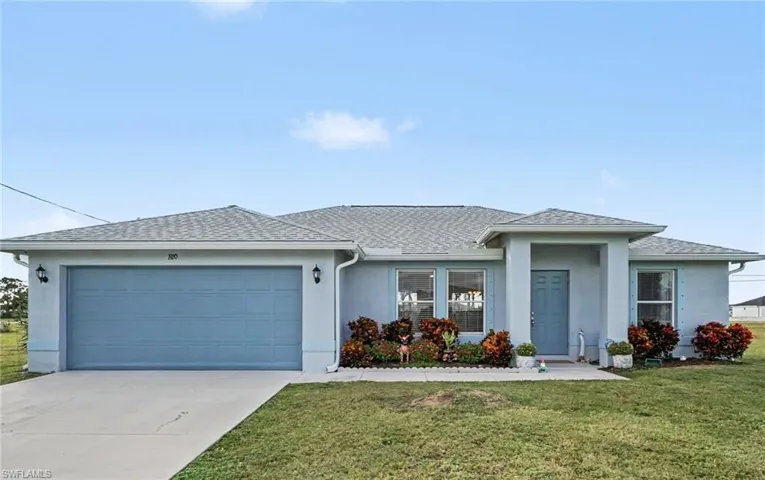 Single-story exterior featuring a light blue stucco facade, attached two-car garage, covered entryway, and concrete driveway