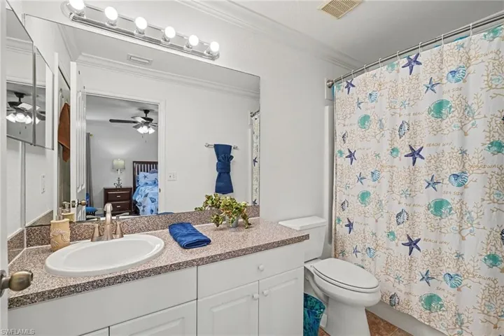 Bathroom featuring a white vanity with a neutral solid-surface countertop, an integrated oval basin, a large wall-mounted mirror, overhead multi-bulb lighting, and a bathtub-shower combination