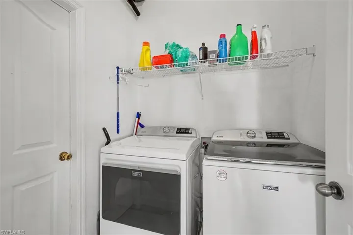 Laundry area featuring white appliance cabinetry, wall-mounted wire shelving, and paneled doors with metallic hardware