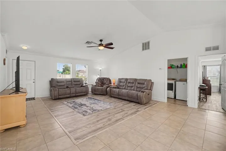 Living space featuring vaulted ceilings, wood-finish flooring, neutral wall paint, and a ceiling fan